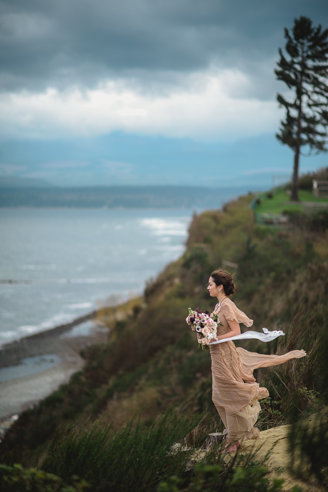 Bride on Cliff in Wind Colours of the Wind Erin Wallis Photography West Coast Weddings Magazine