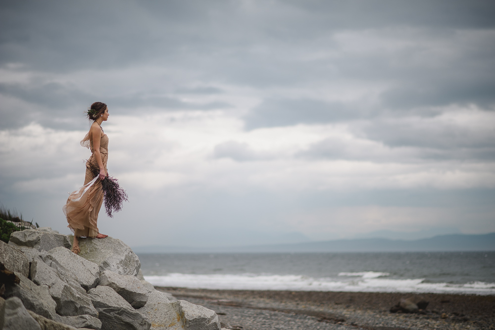 Bride on Rocks looking at oceanColours of the Wind Erin Wallis Photography West Coast Weddings Magazine