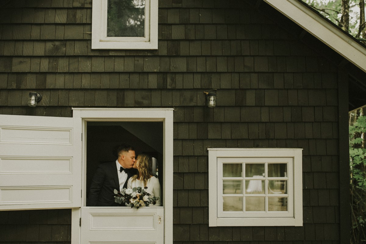 Newlyweds Kiss in Barn Door Elegant Woodland West Coast Weddings Magazine Vancovuer