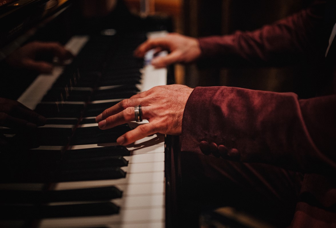 A Glamorous Holiday Wedding Groom Plays Piano with Wedding Band