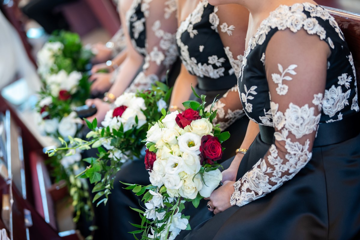 Bridesmaids in black and white gowns carrying white dendrobium orchid bouquets