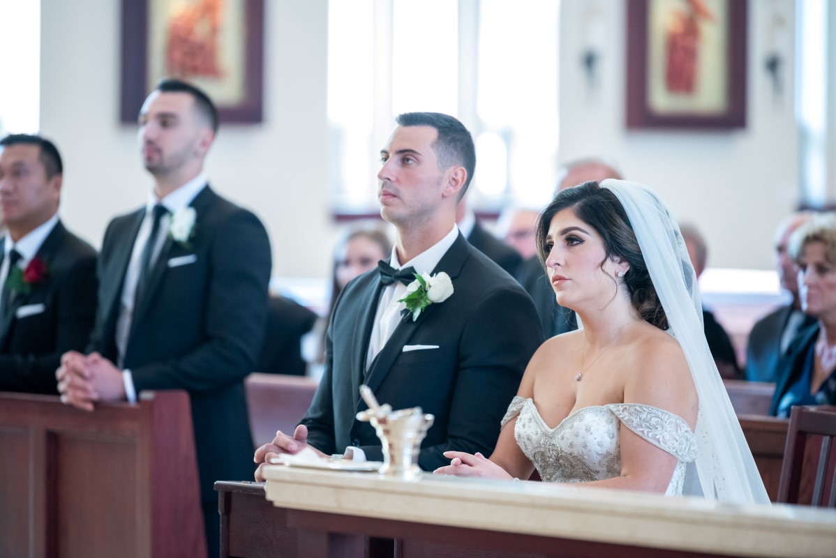 Wedding couple kneel at the alter of Our Lady of Assumption Church in Vancouver