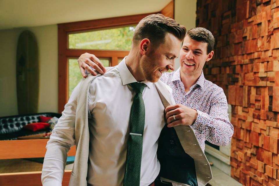 Tofino Elopement Groom puts on his jacket with best man before ceremony on Tonquin Beach