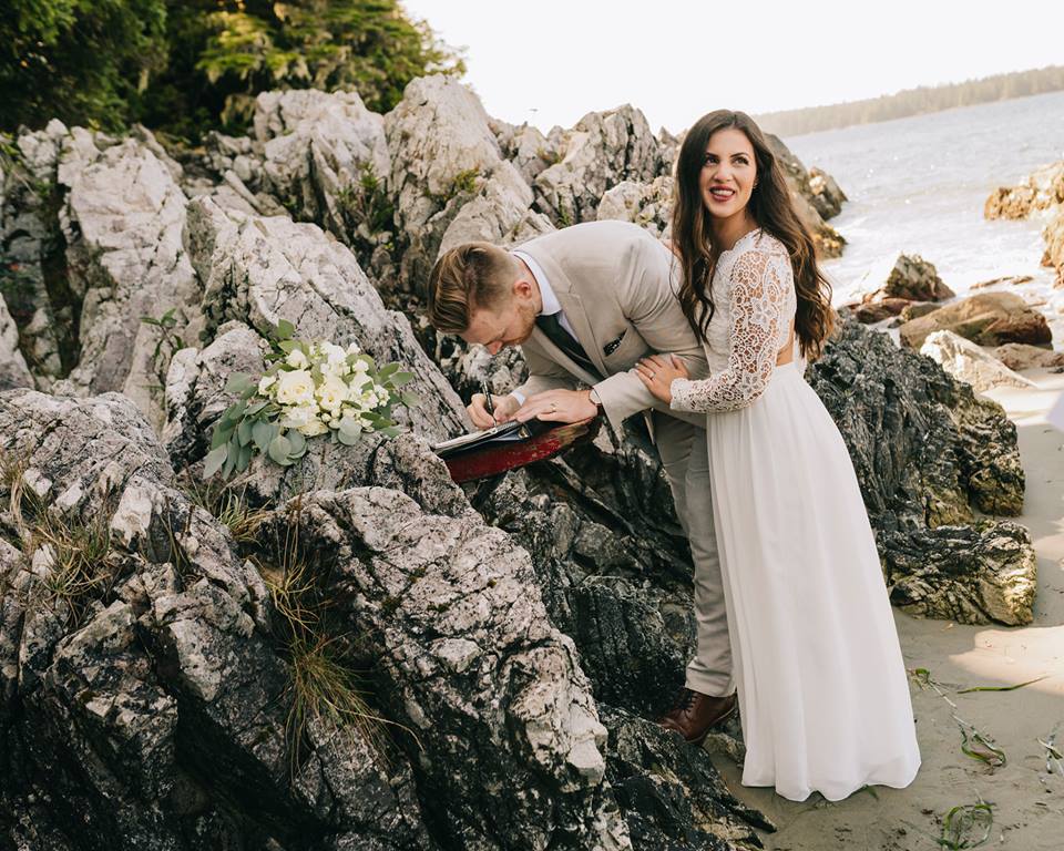 Tofino Elopment Couple signing the registrar on the rocks of Tonquin Beach Vancouver Island