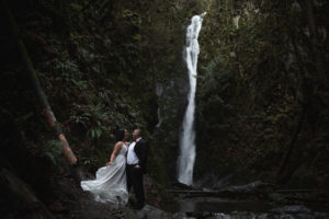 Bridal couple pose in front of waterfall on Vancouver Island