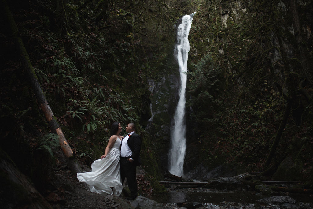 Bridal couple pose in front of waterfall on Vancouver Island