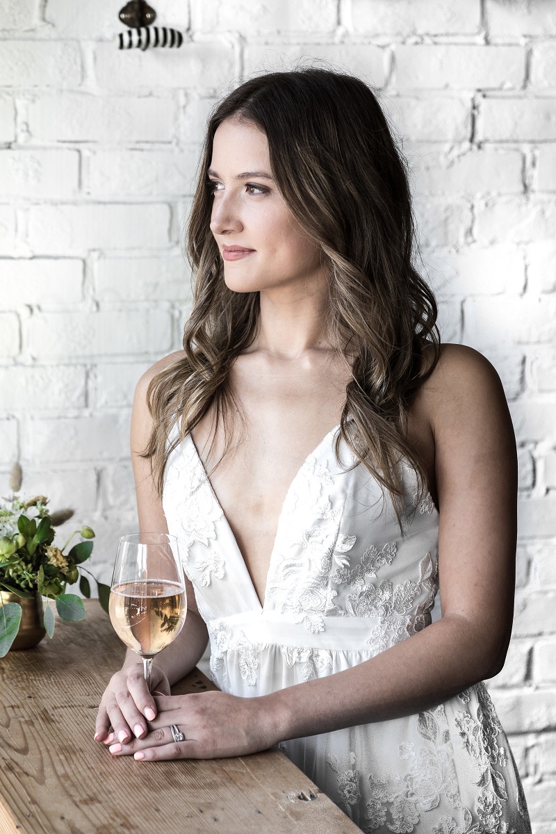 Chic City Bride in Park and Fifth Co weddin gown holding glass of wine at Burdock & Co in Vancouver