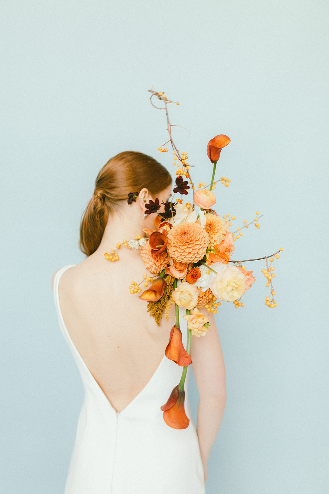 Open Back Bridal Gown with orange bridal bouquet in Vancouver Wedding Magazine