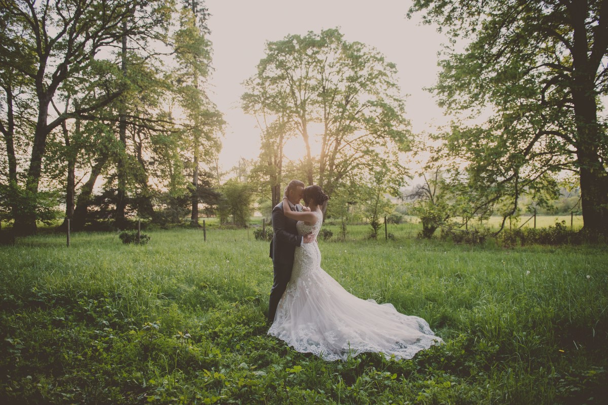 Newlyweds in grass field with bridal train of lace Cowichan Valley