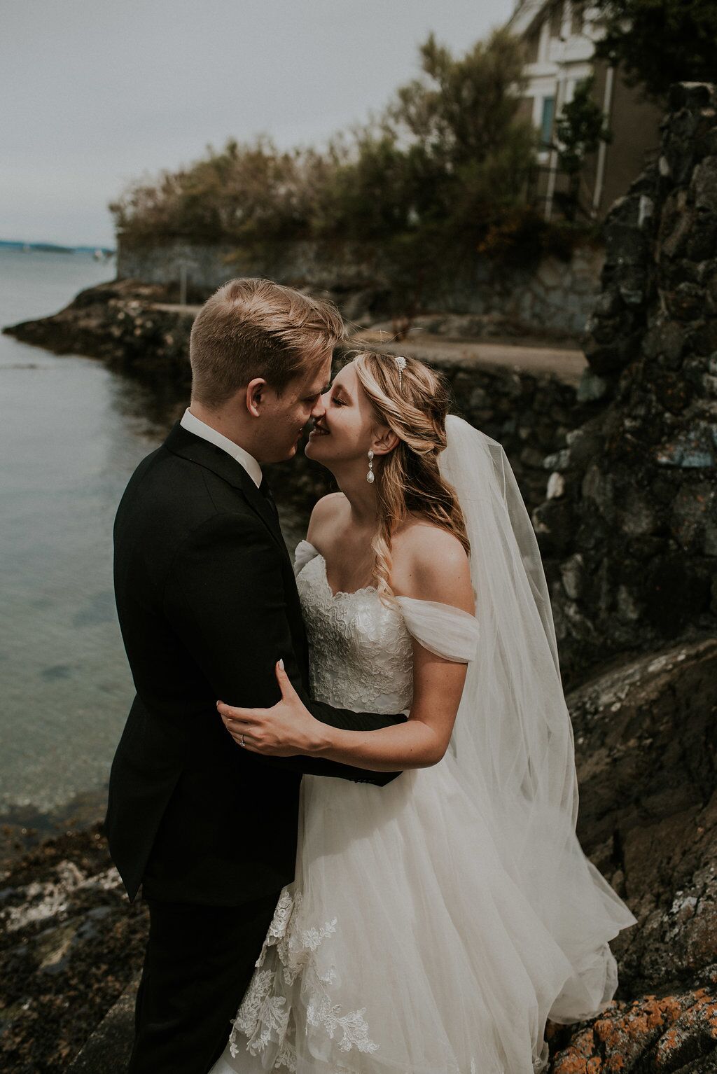 Romantic Newlyweds kiss above the ocean water on Vancouver Island