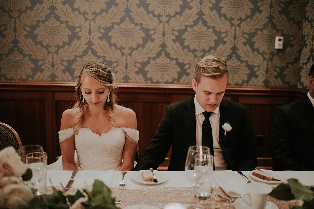 Romantic Newlyweds bow their head in prayer at Oak Bay Beach HOtel reception meal