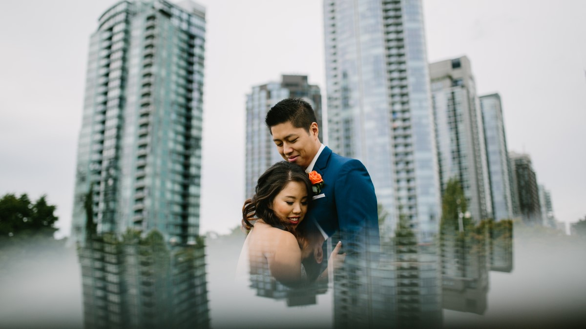 Bride and groom artsy photo with Vancouver sky line behind them