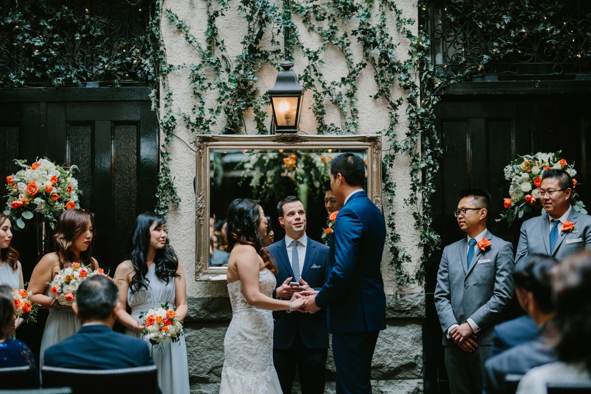 Chinese Fusion Wedding couple exchange vows in front of ivy backdrop in Vancouver