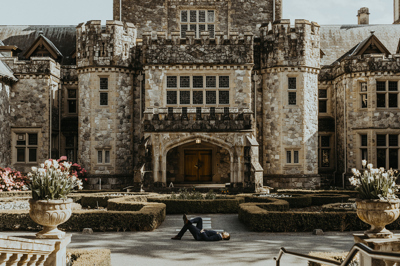 Groom lays on the ground in front of Hatley Castle entrance on Vancouver Island