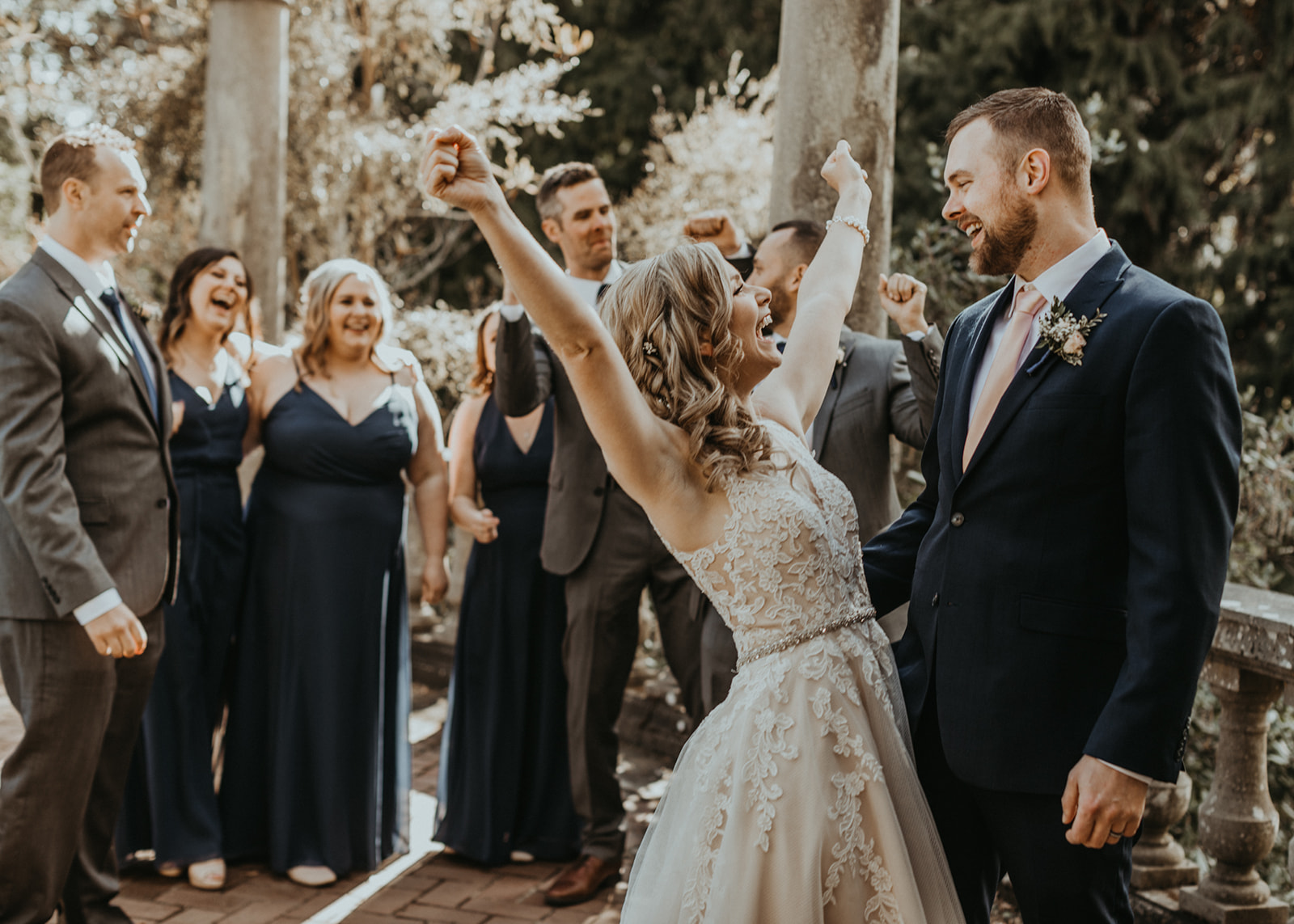 Bride throws her arms up in happiness wearing Rebecca Ingram gown by Blush Bridal Vancouver Island