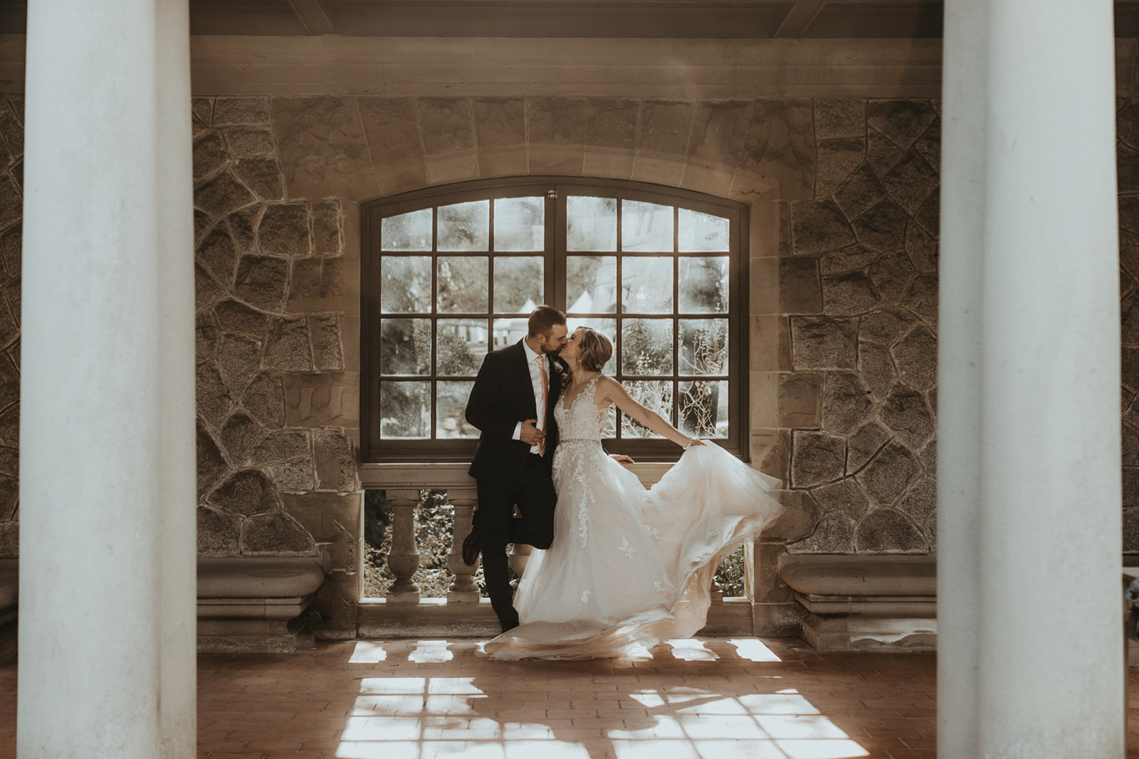 Newlyweds in front of Hatley Castle window as sun pours through on them