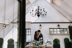 Wrought iron black chandelier in white wall venue with bride and groom