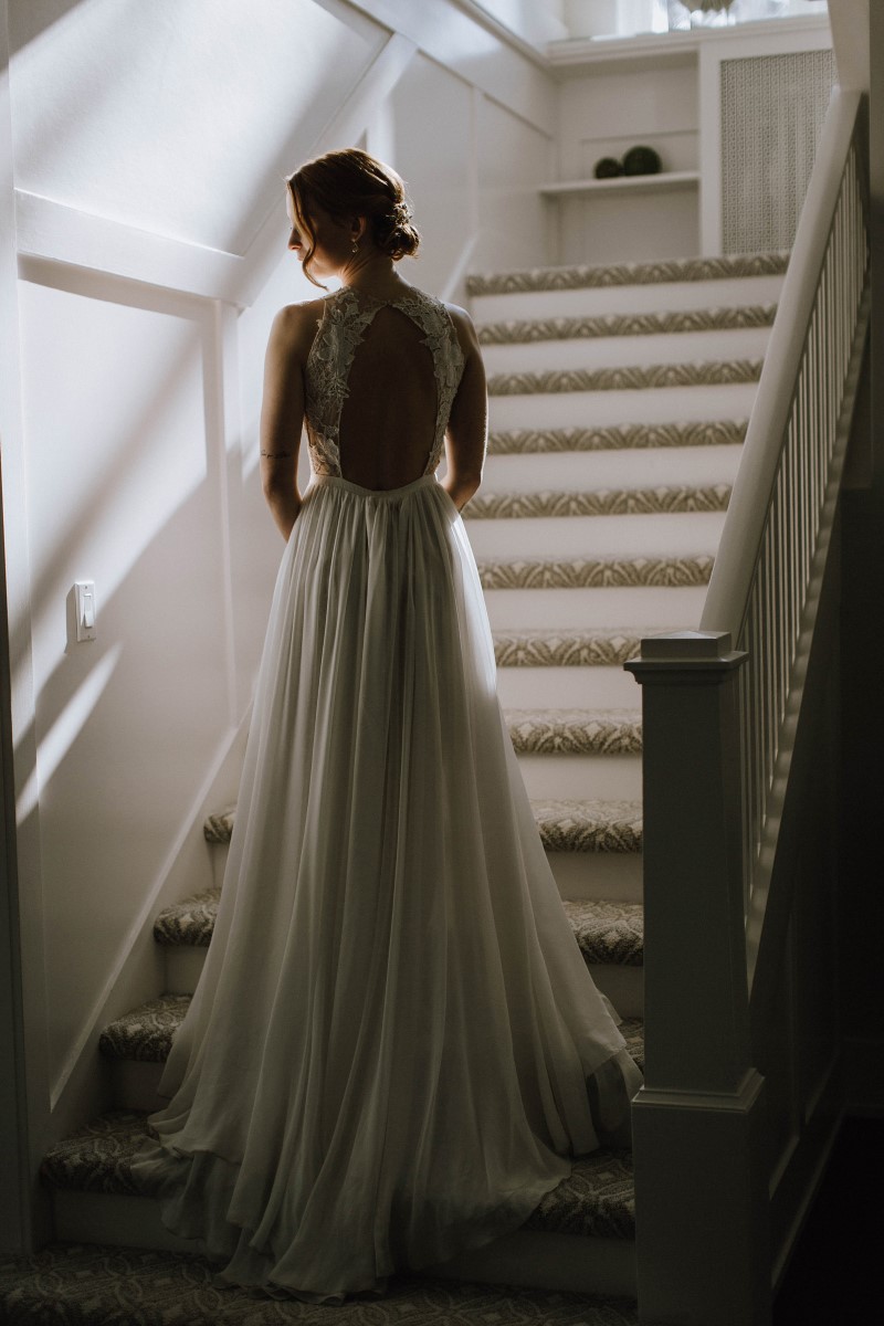 Sophisticated Bride in flowing lace gown on staircase of Maple Bay Manor West Coast Weddings Magazine