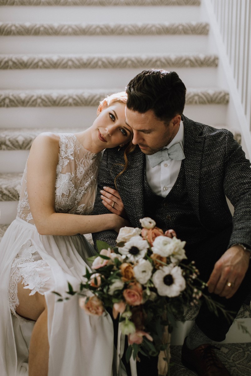 Sophisticated Bride leans on groom's shoulder with bouquet