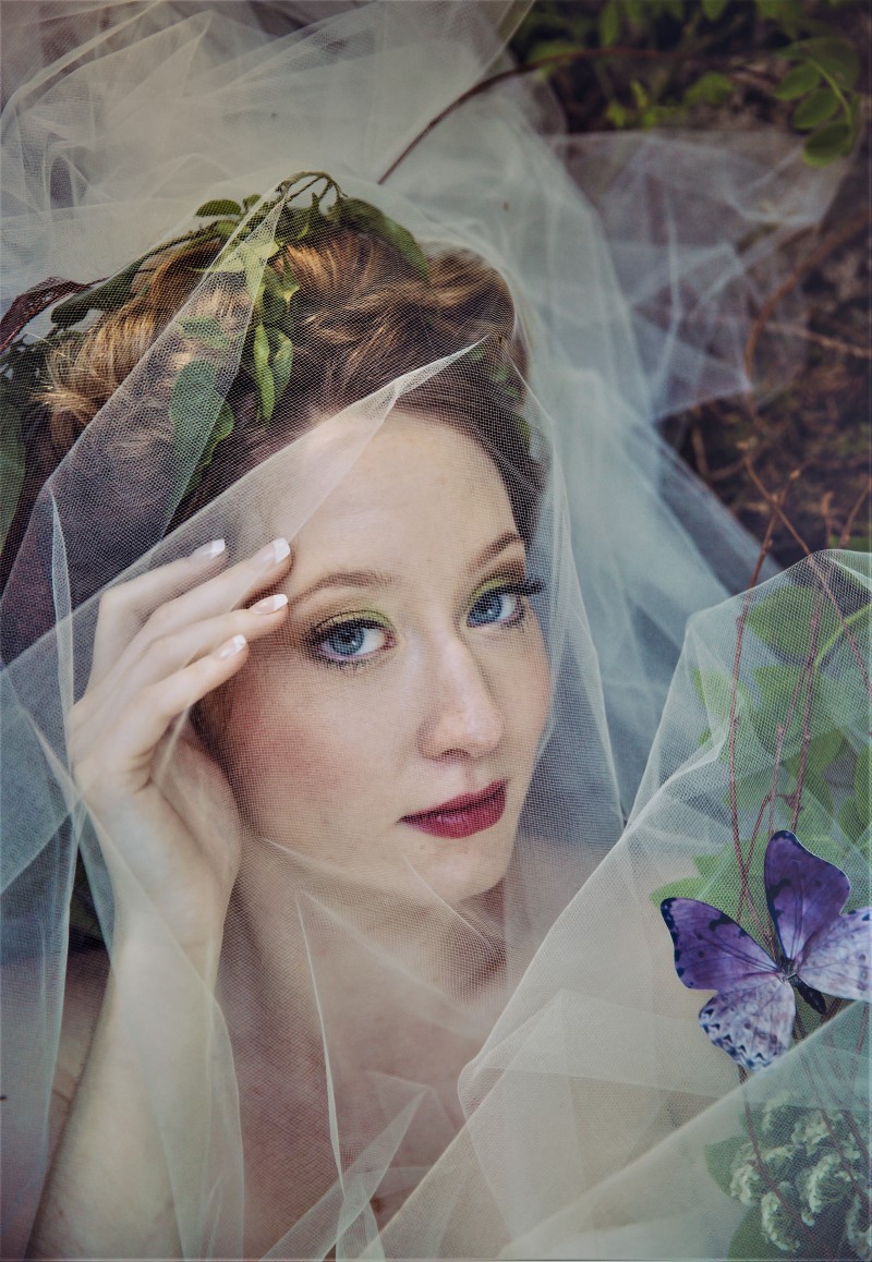 Whimsical Woodland Bride with butterfly in her hair and veil over her face