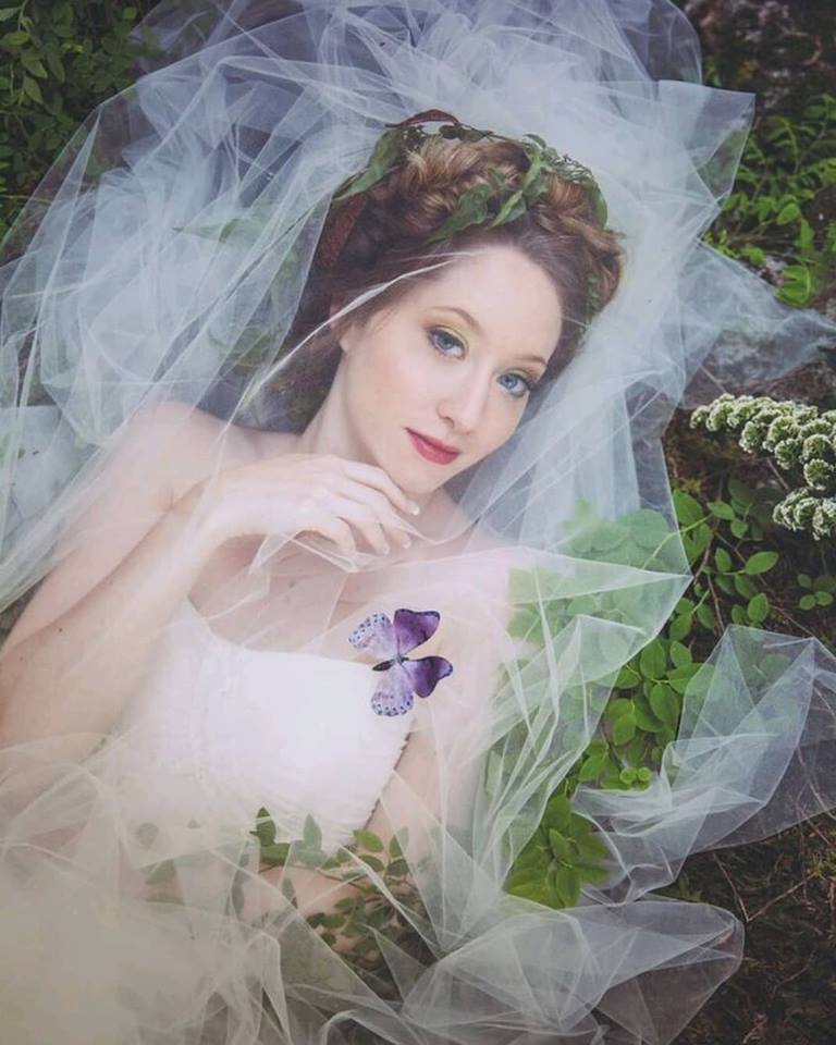 Bride covered with veil has butterfly land on her