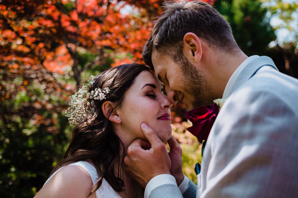 Newlyweds kiss in garden by Megan Maundrell PHotography