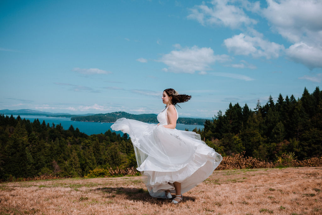 Bride swirls her white gown skirt along the ocean edge of Vancouver Island