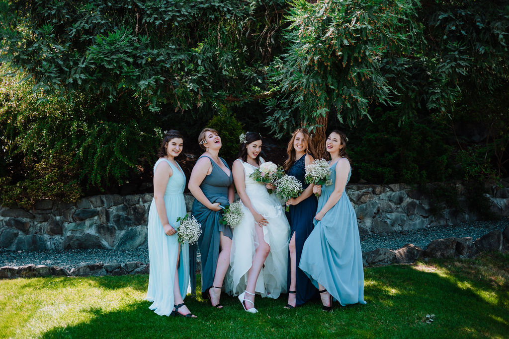 Bridesmaids in shades of blue and green dresses with bride