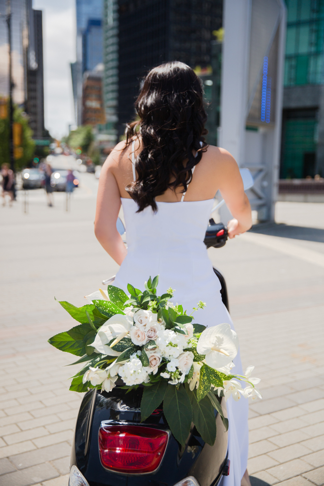 City Chic Bride on bike with bouquet behind her on city street