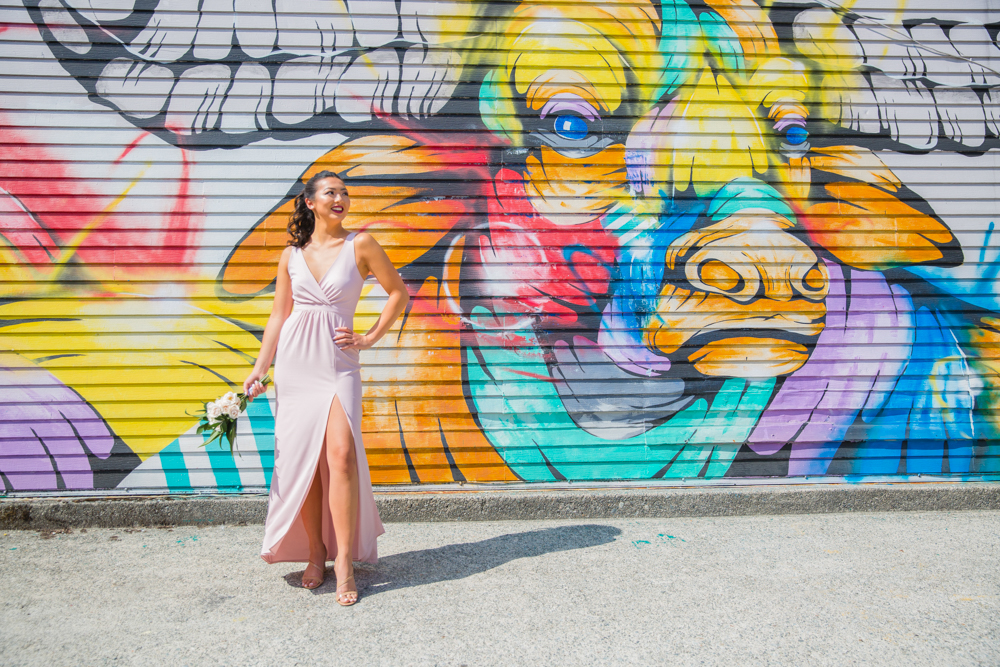 Bride in white gown in front of wall graffiti