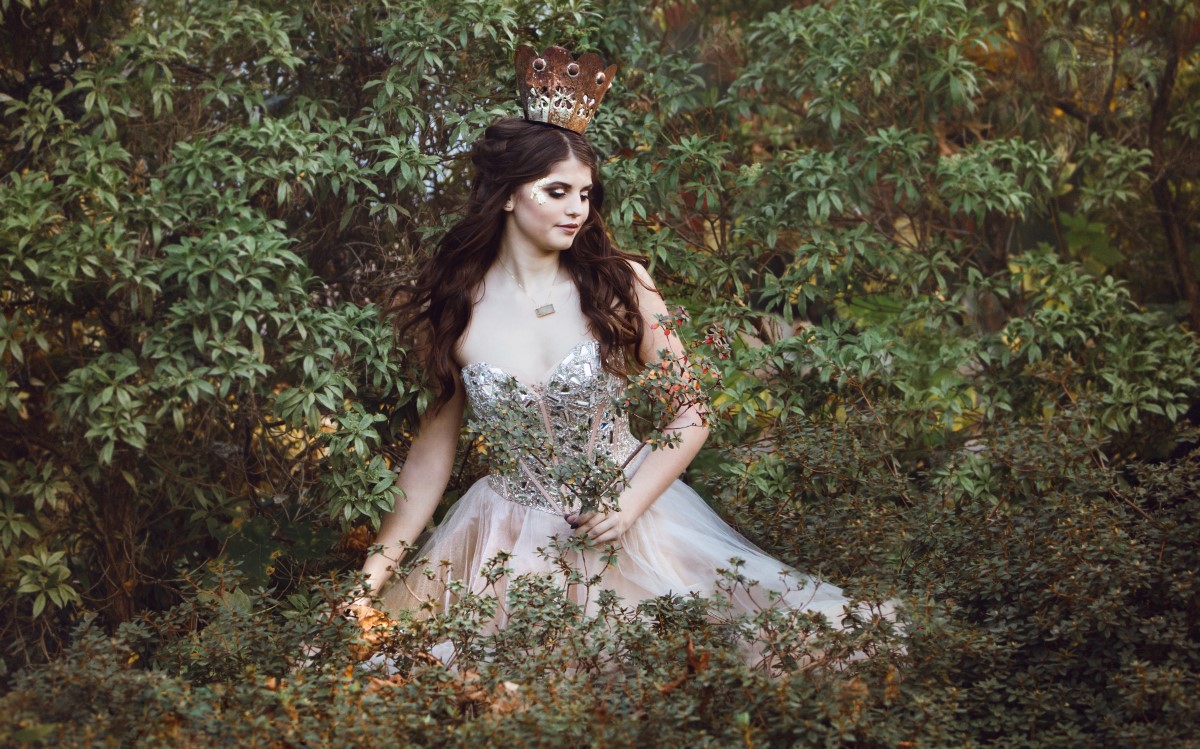 Bride sitting in field in royal inspired gown and long hair