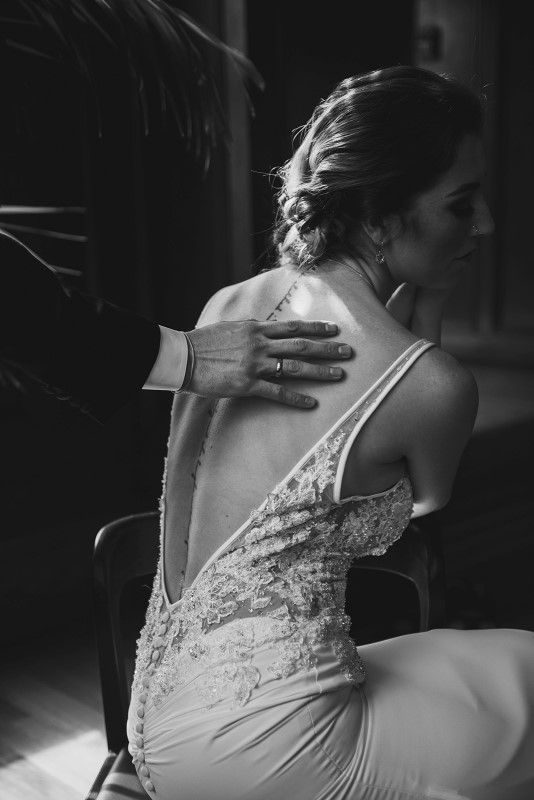 Groom puts hand on back tattoo of bride by KGOODPhoto