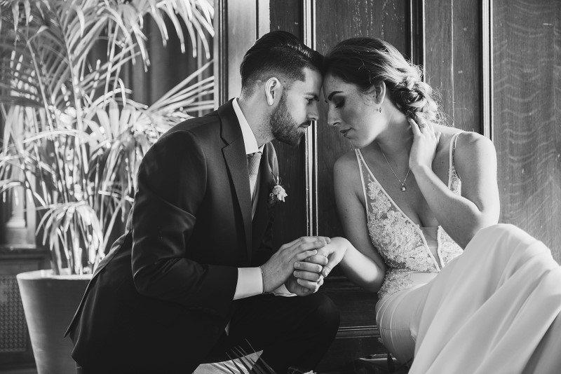 Bride and Groom hold each other's hands in window seat of Fairmont Empress