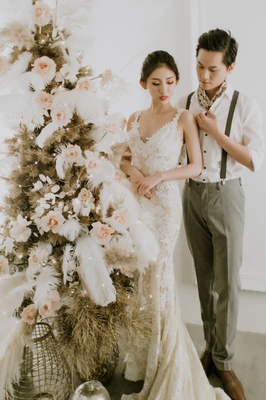 Dreamy White Wedding bride and goom standing next to frosted pine tree decorated with flowers