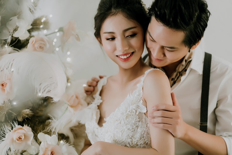 Dreamy White Wedding groom holding smilling bride with feather in her hand