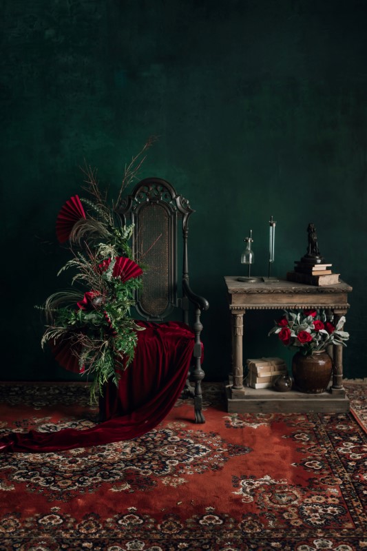 West Coast Weddings Magazine green wall, Persian rug, chair, table and floral arrangement with red fans Blushing Vintage Rentals