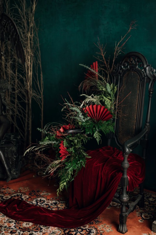 Culture Fusion chair with red cloth and green floral decor with red fans Arizel Studio