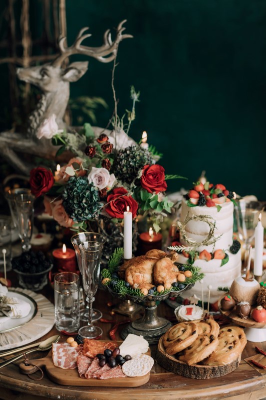 Culture Fusion reindeer statue on table with naked wedding cake charcuterie platter, roasted chicken, candles, floral arrangements