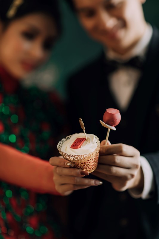 Culture Fusion bride and groom holding up dessert cup and cake pop