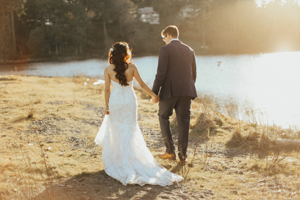 Steal of a wedding bride and groom walking shoreline holding hands shades of white bridal