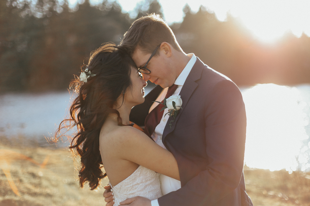 West Coast Weddings Magazine bride and groom by the water holding each other and looking into each other's eyes