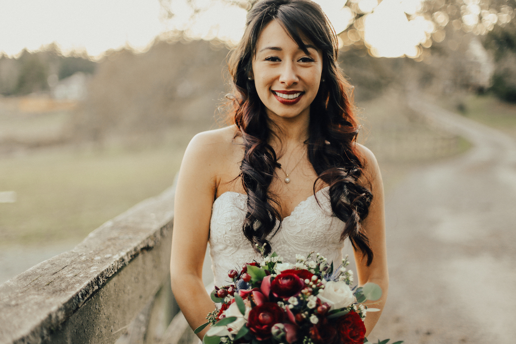 West Coast Weddings Magazine bride with curly long hair holding bouquet next to fence erin bradley