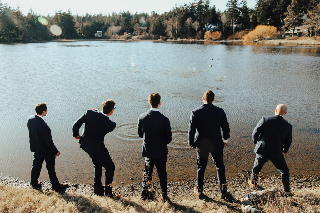 Steal of a Wedding groom and his groomsmen skipping stones by the water