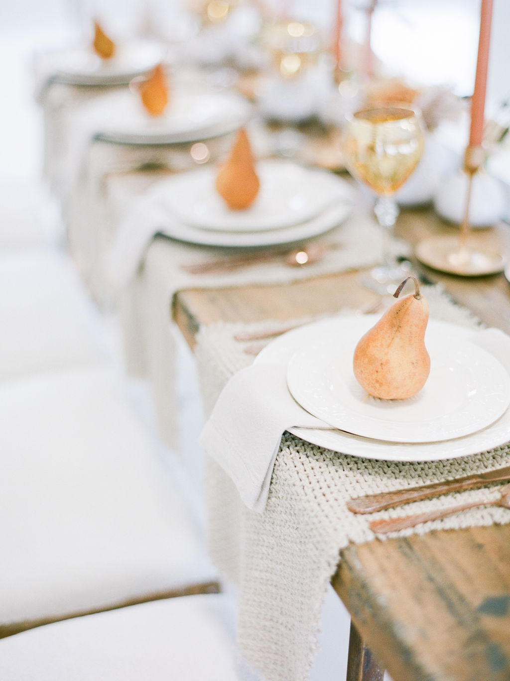 Gold pairs sit upon white plates on wood long table for newlyweds