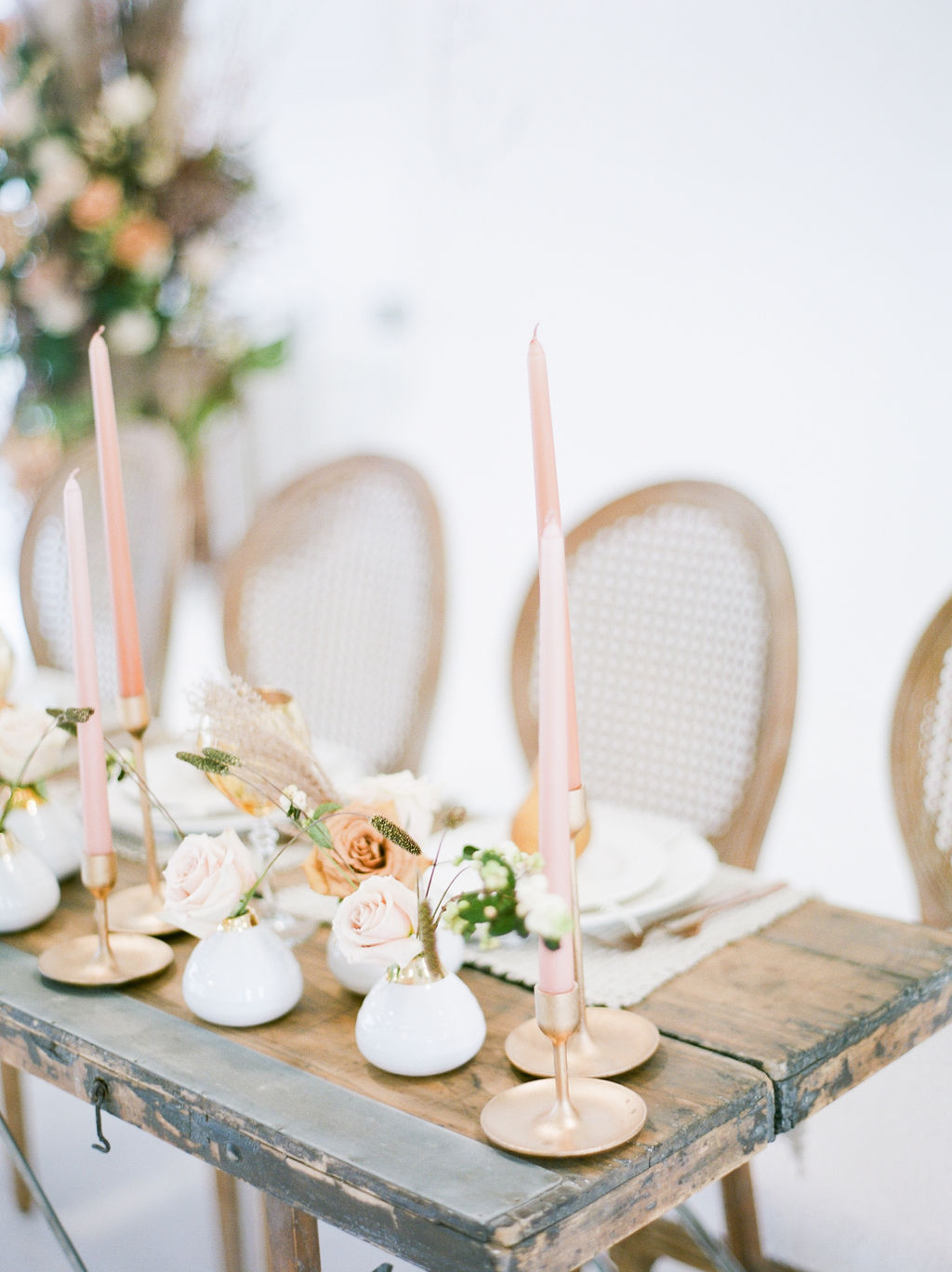 Grey wood long sweetheart table with rattan chairs and gold candlesticks and pears