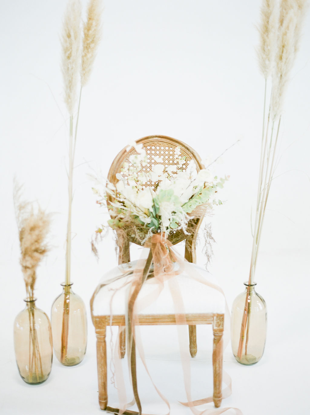 Bouquet of pampas grass and roses sit on white chair by Deborah Lee Designs Vancouver