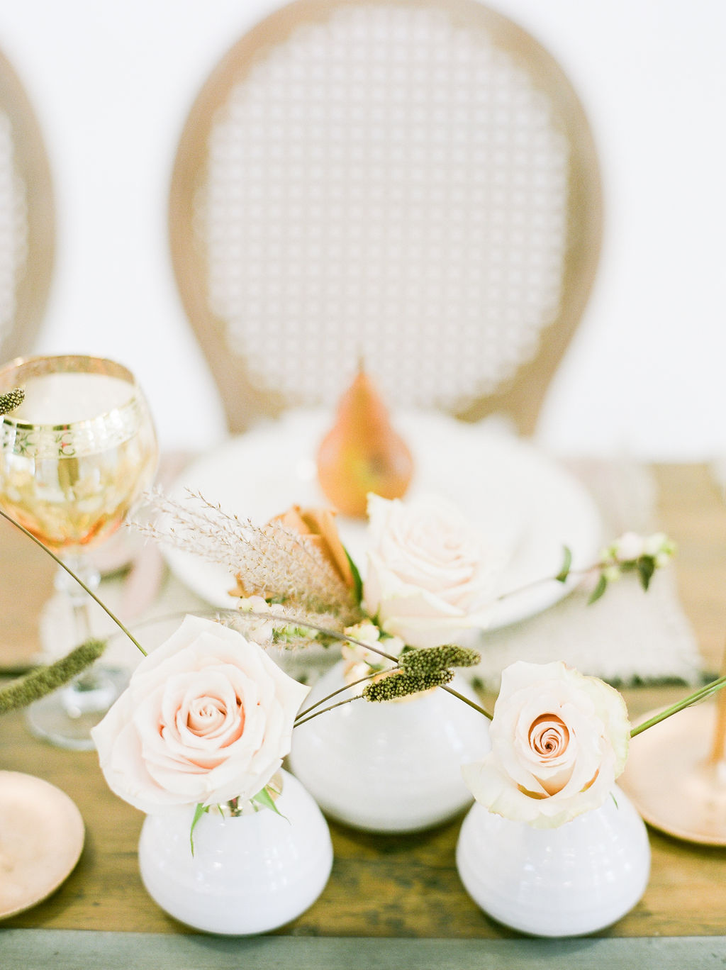 Golden pears and blush roses sot pm white dishes at wedding table