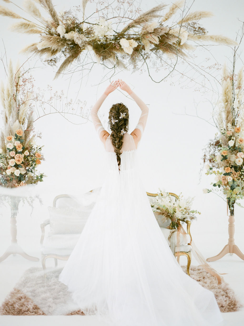 Bride holds her arms above her with floral on each side of her by