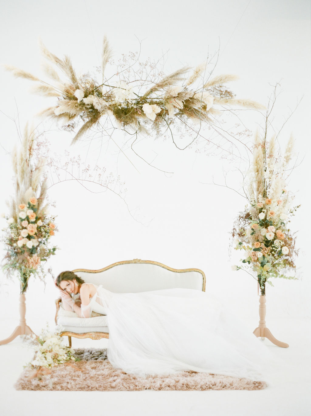 Bride on white settee surrounded by floral by Deborah Lee Designs Vancouver