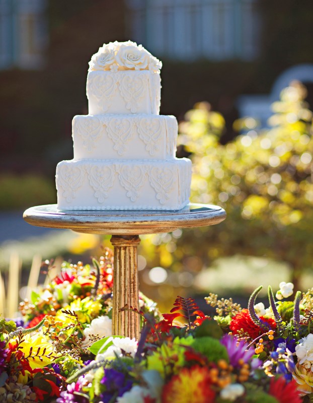 White Wedding Cake Sitting in Flower Bed at Butchart Gardens by Ooh La La Cupcakes